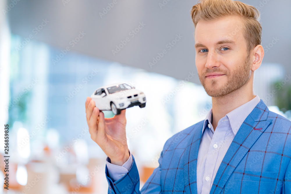 汽车保险业务理念穿着西装的高加索商人用手展示汽车模型