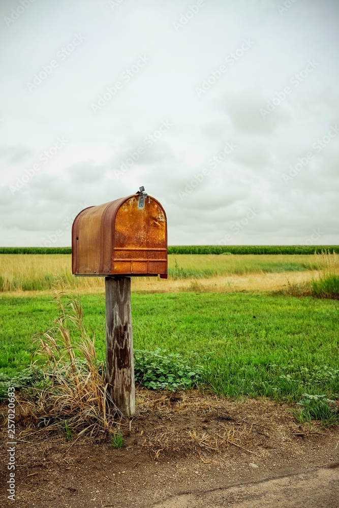 An old rusty mailbox in a field.