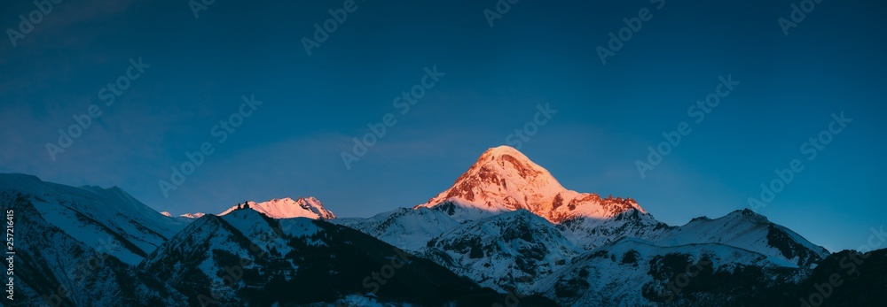 乔治亚州。卡兹贝克山在冬季日出时被雪覆盖。清晨的黎明为平克托的山顶上色