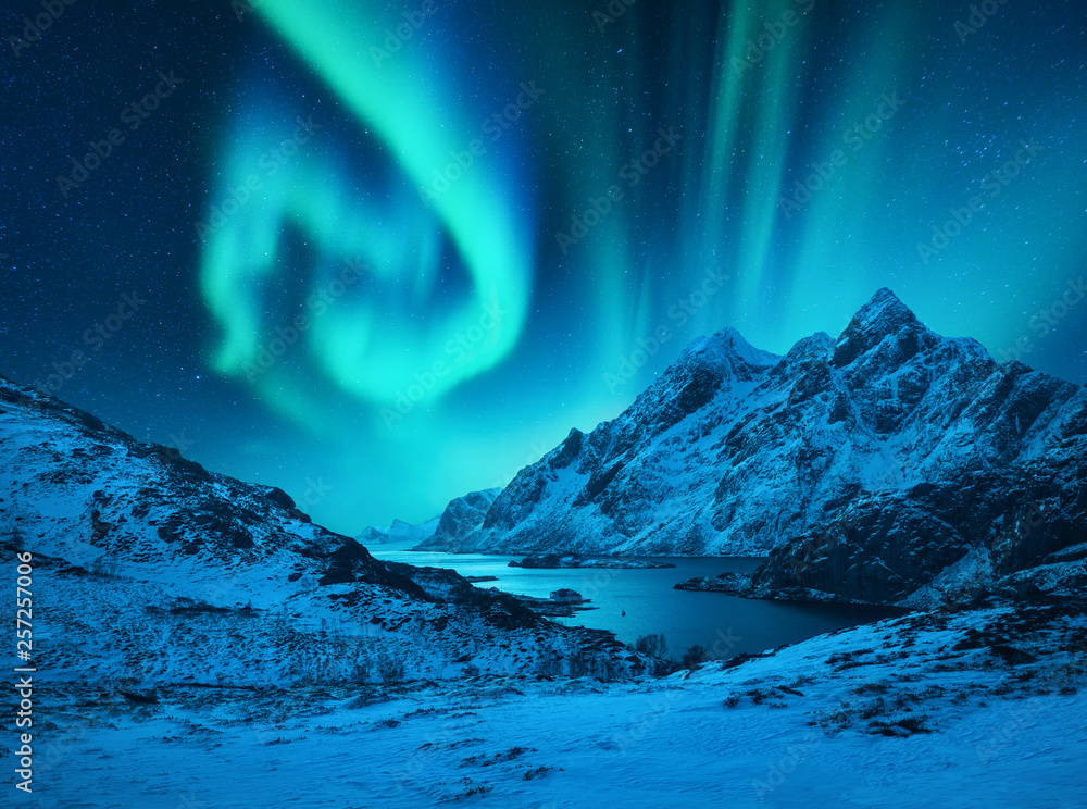 挪威罗弗敦群岛白雪皑皑的山脉上的北极光。冬天的北极光