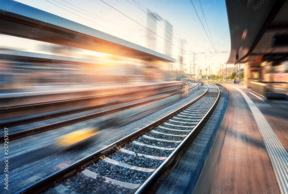 Railway station with motion blur effect at sunset. Industrial landscape with railroad, blurred railw
