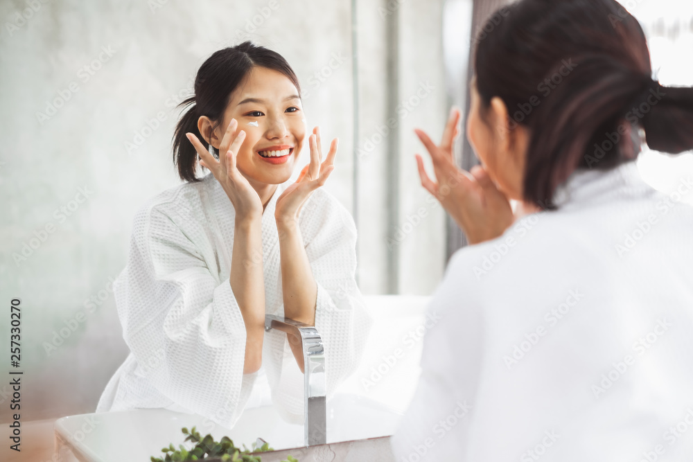 亚洲女性在镜子前清洁面部，护肤和美容概念