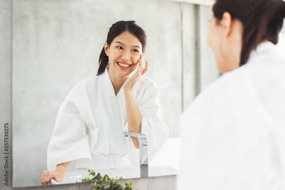 亚洲女性在镜子前清洁面部，护肤和化妆品去除概念