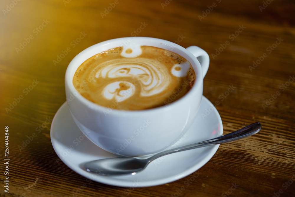 Bear latte art in cappuccino cup on wooden table. Pattern on coffee foam.White cup with coffee on th