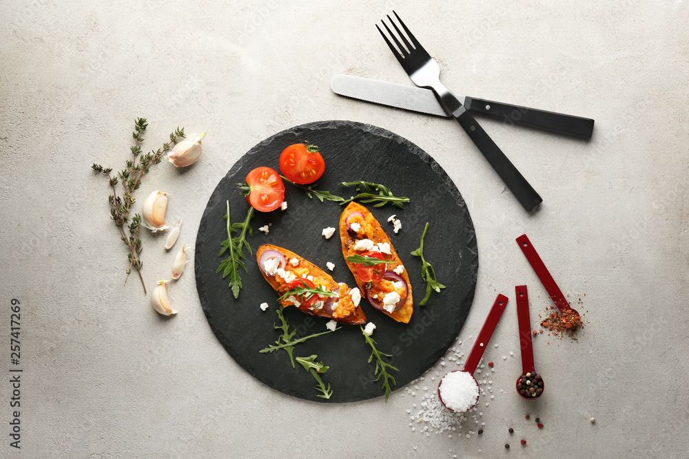 Slate plate with baked sweet potato on grey background