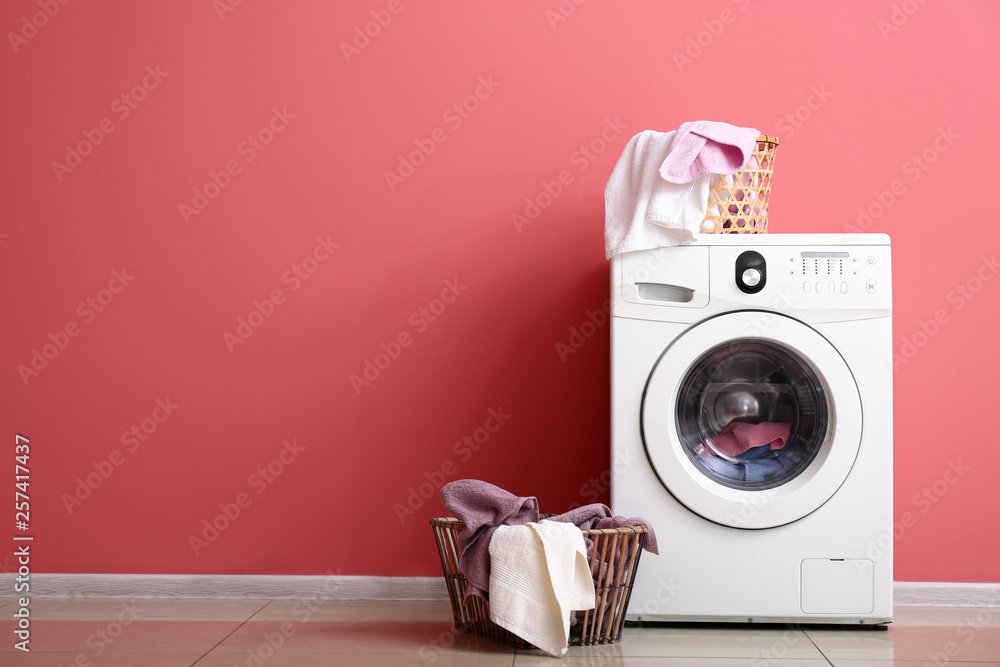 彩色墙附近的现代洗衣机和洗衣房