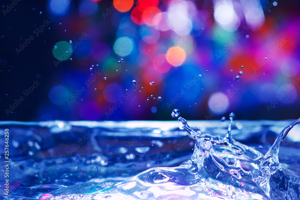抽象的彩色泼水背景，带有水滴和散焦效果