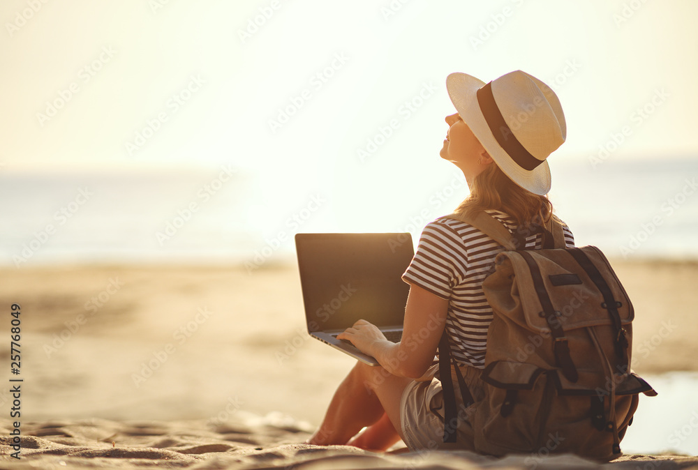 年轻女子在海滩上用笔记本电脑在大自然中工作