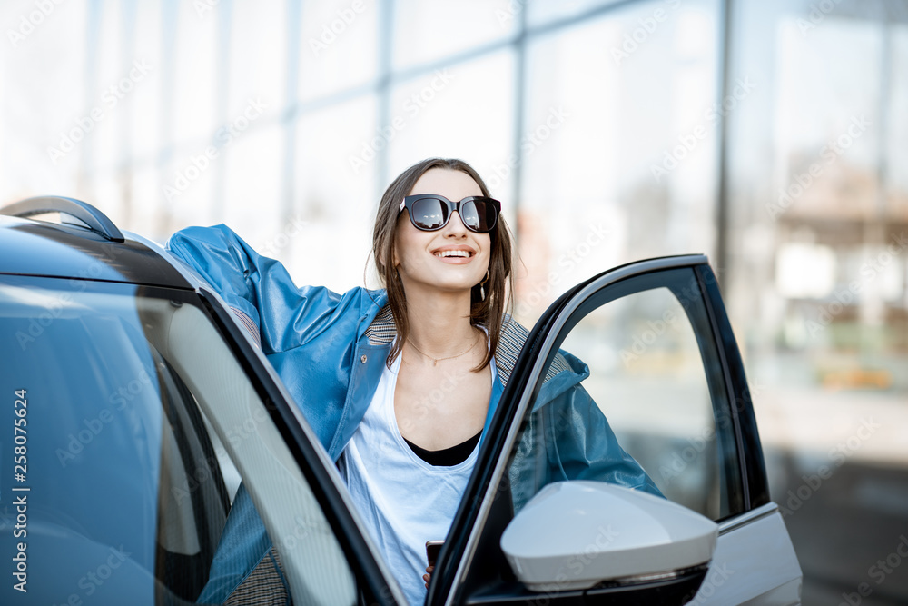 一个年轻快乐的女人站在户外现代汽车附近的肖像