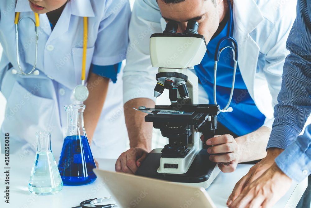 一群穿着实验室外套的科学家在实验室工作，检查实验室的生物化学样本