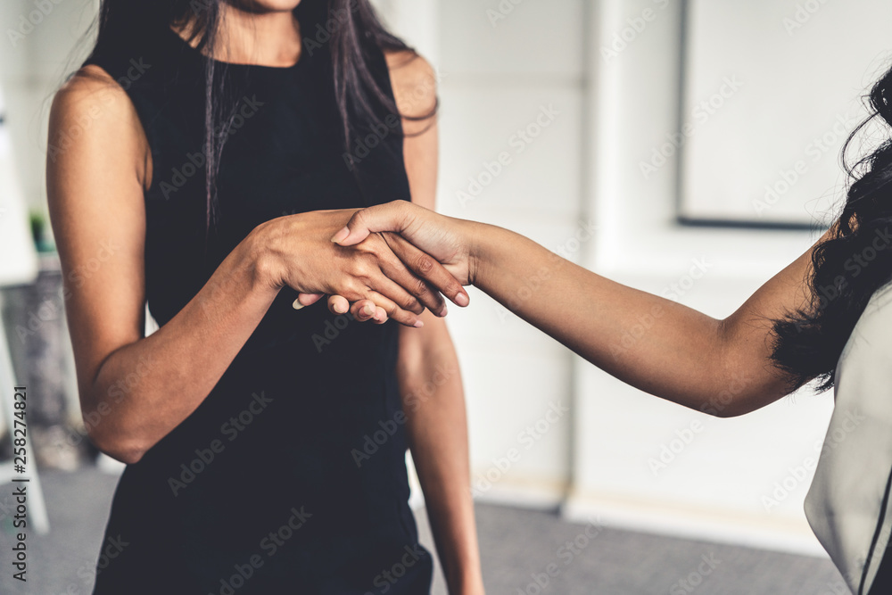 两位年轻的亚洲女商人在办公室握手。商业朋友和社区理念。