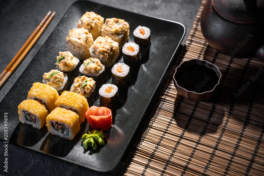 美味的寿司卷用筷子夹在黑色桌子上