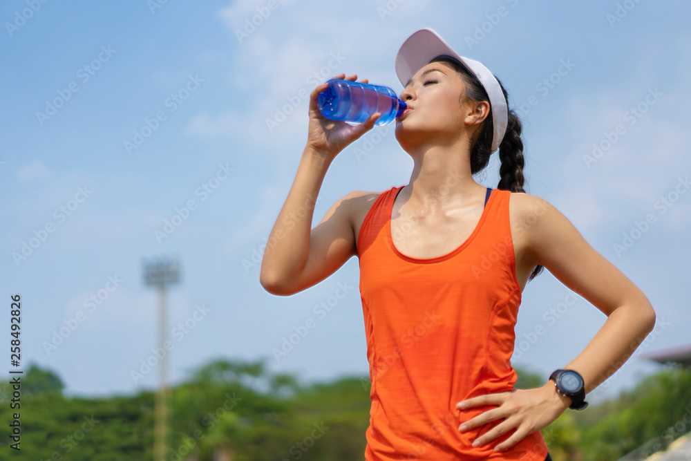 女跑步者正在喝水。训练结束后
