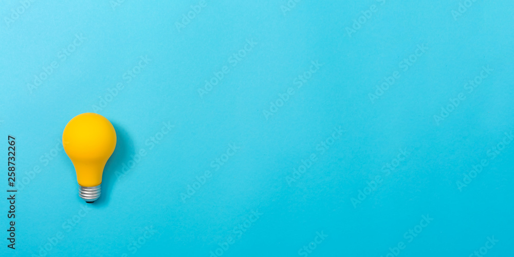 Colored light bulb on a blue paper background