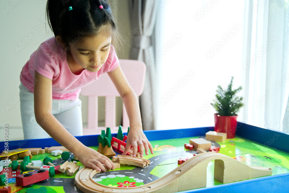 年轻的亚洲小可爱在家的桌子上玩木制玩具。她正在连接木栏杆f