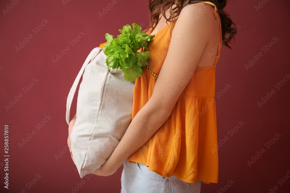 绿色背景环保袋里装着新鲜蔬菜的年轻女子