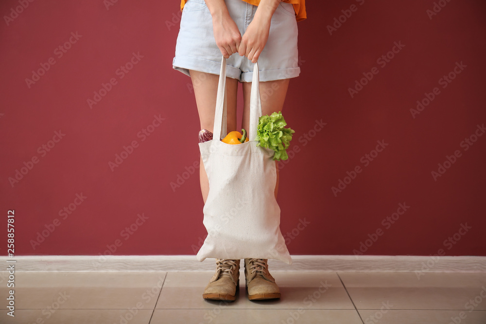 绿色墙附近的环保袋里装着蔬菜的年轻女子