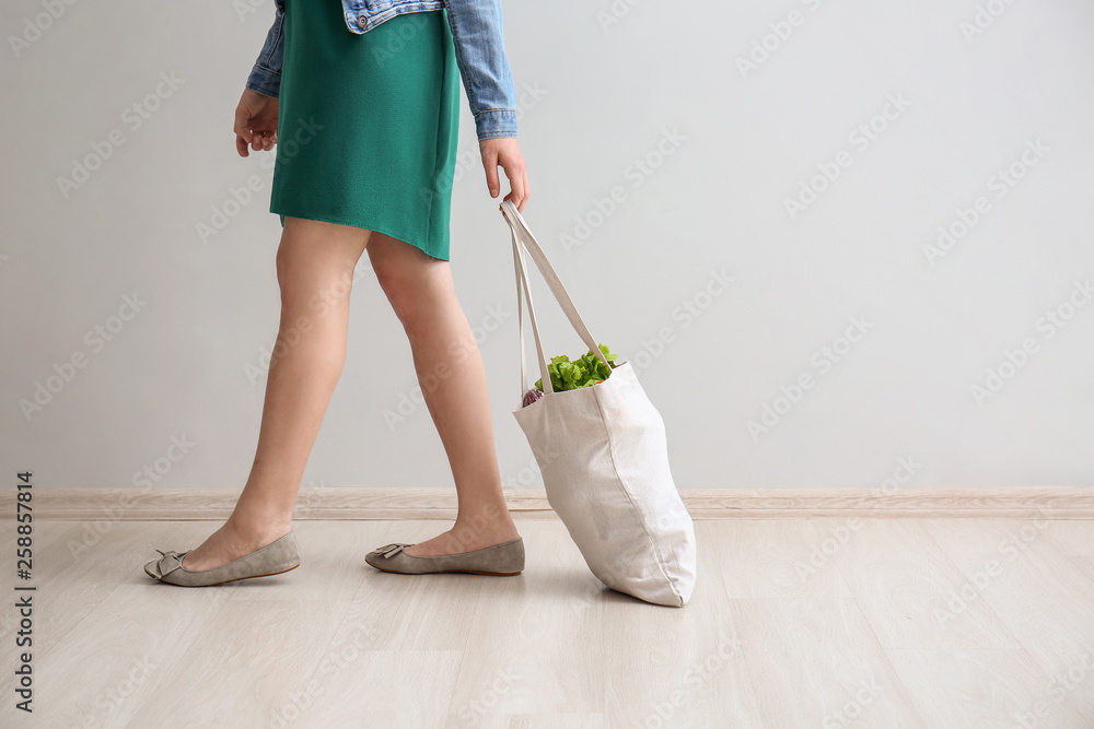 光墙附近环保袋里装着蔬菜的年轻女子