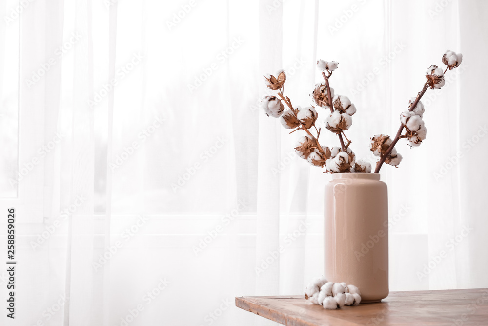 靠近窗户的桌子上有棉花树枝的花瓶