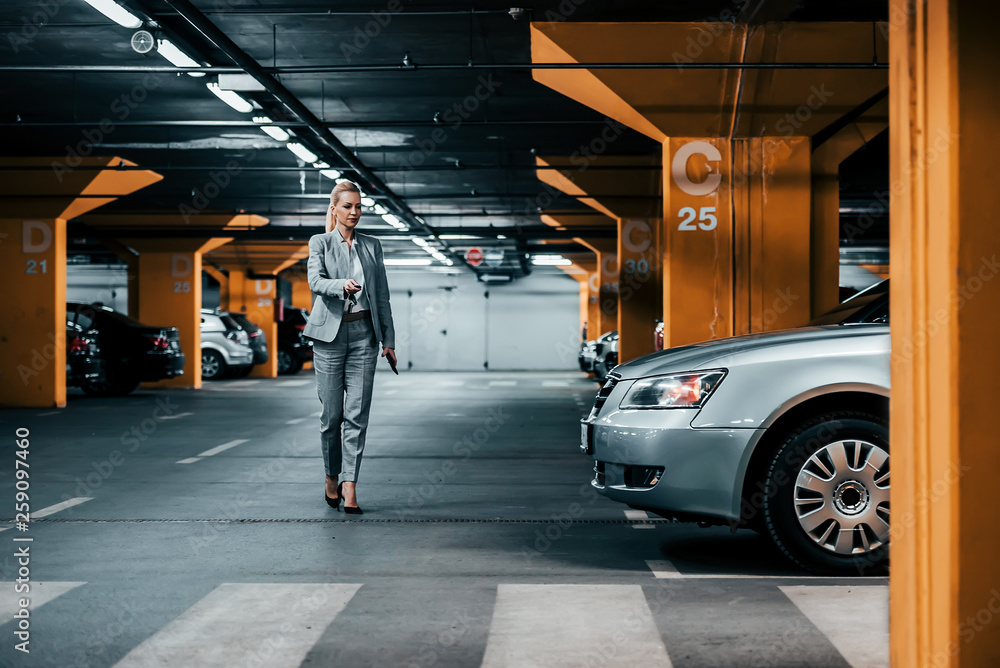 成功的女商人在地下停车场走向她的车。