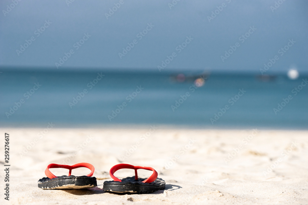 度假时，凉鞋放在泰国海边岛上的白黄色沙滩上