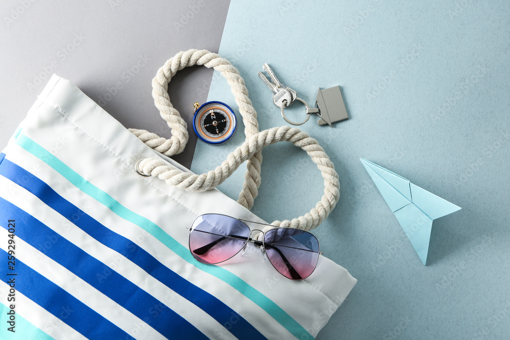 沙滩包、太阳镜、指南针和彩色背景纸飞机。旅行概念