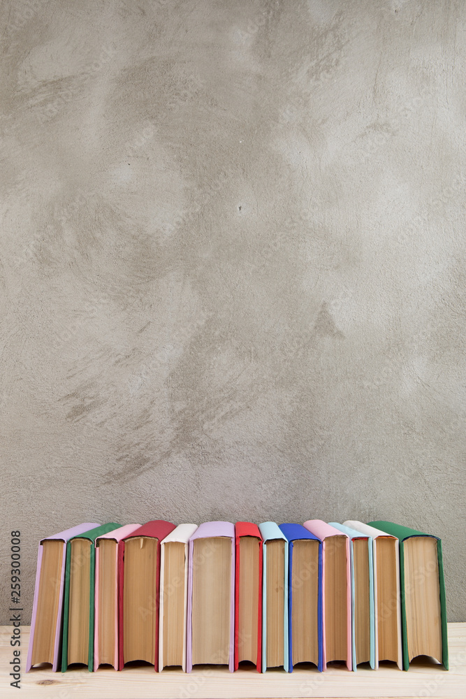 教育和阅读理念——木桌上的一组彩色书籍，混凝土墙黑板