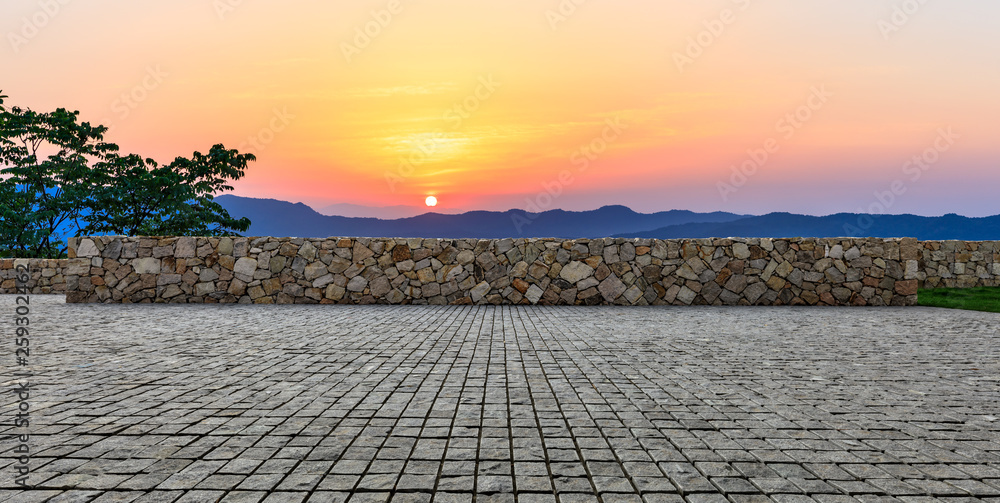空旷的方形砖地面和日落时美丽的山地自然景观