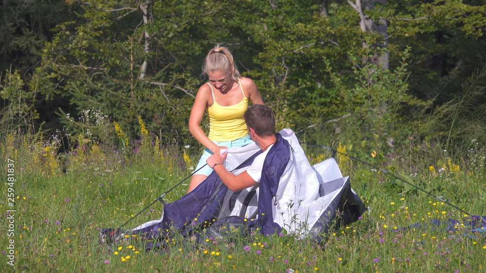 一对无忧无虑的夫妇在夏季露营旅行中搭帐篷玩得很开心。