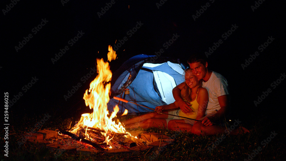 特写：快乐的女人拥抱着用树枝砸着火的男朋友。