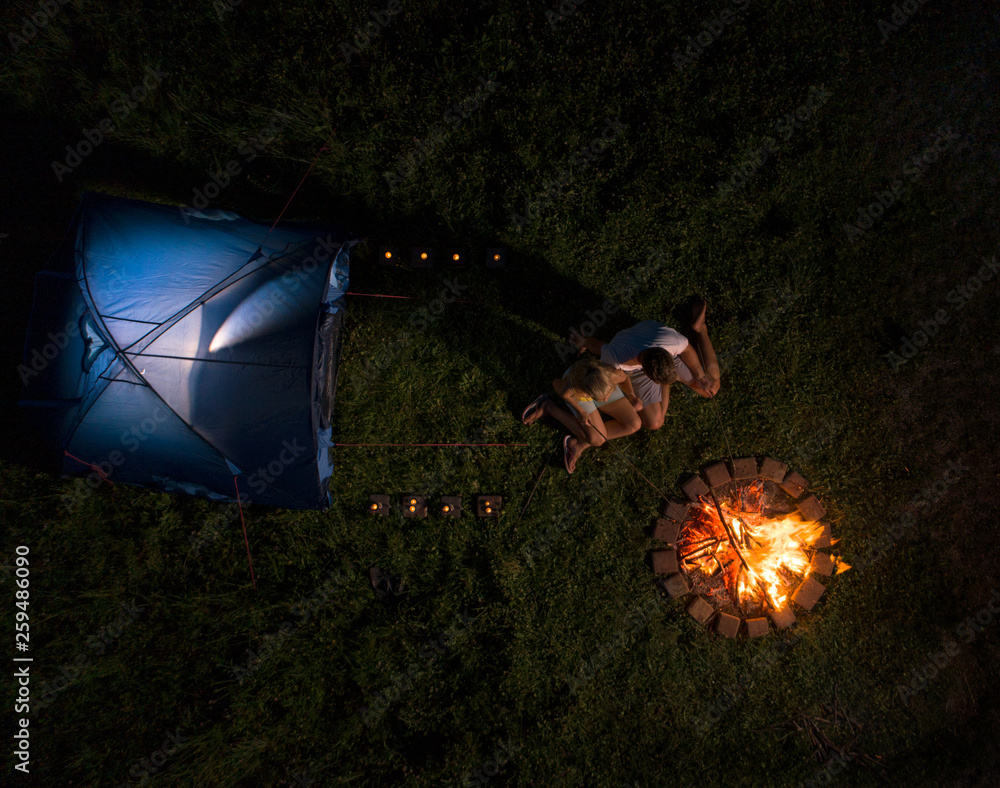 空中飞行：在一次露营旅行中，一对年轻夫妇坐在炉火旁。