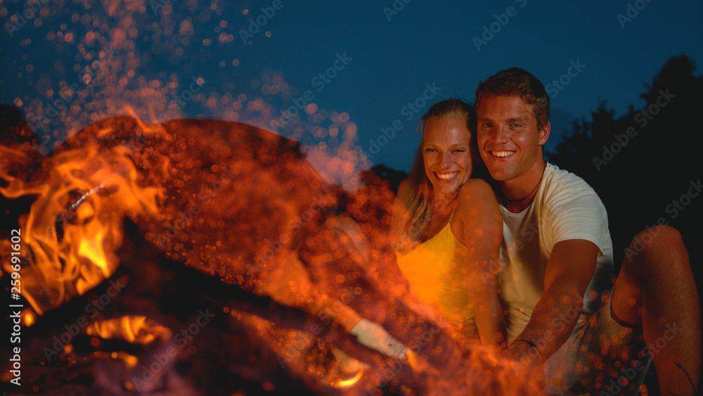 CLOSE UP: Happy woman laughing while she cuddles up to boyfriend by the fire.