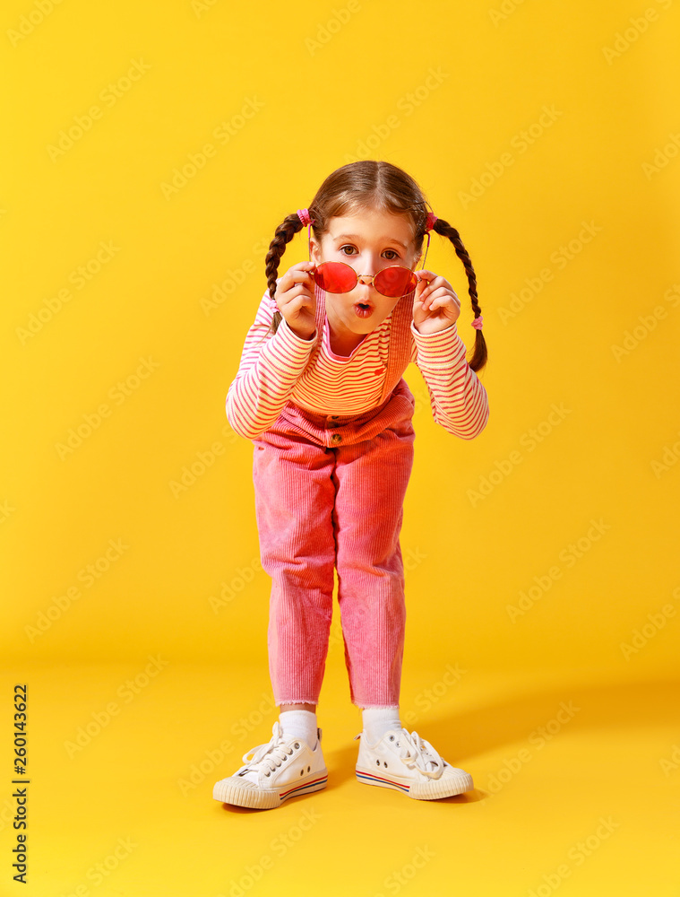 黄色背景下穿着粉色衣服的滑稽有趣的小女孩