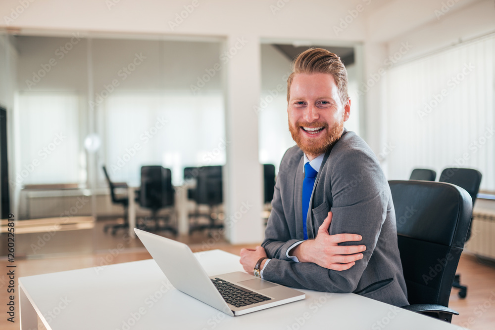 Portrait of smiling confident man in bright office environment.