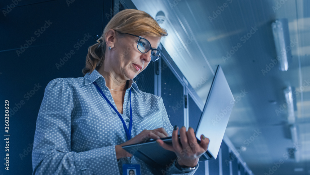 在数据中心：一名女性IT技术人员在L上运行维护程序的低角度人像拍摄