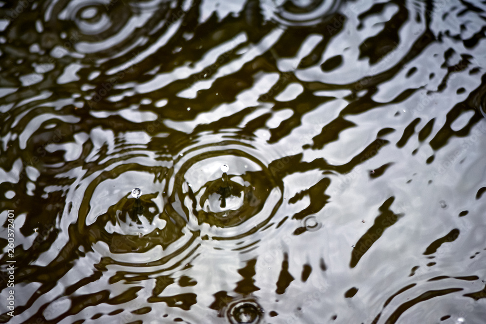 雨滴和圆圈在水上，滴落在水坑表面。