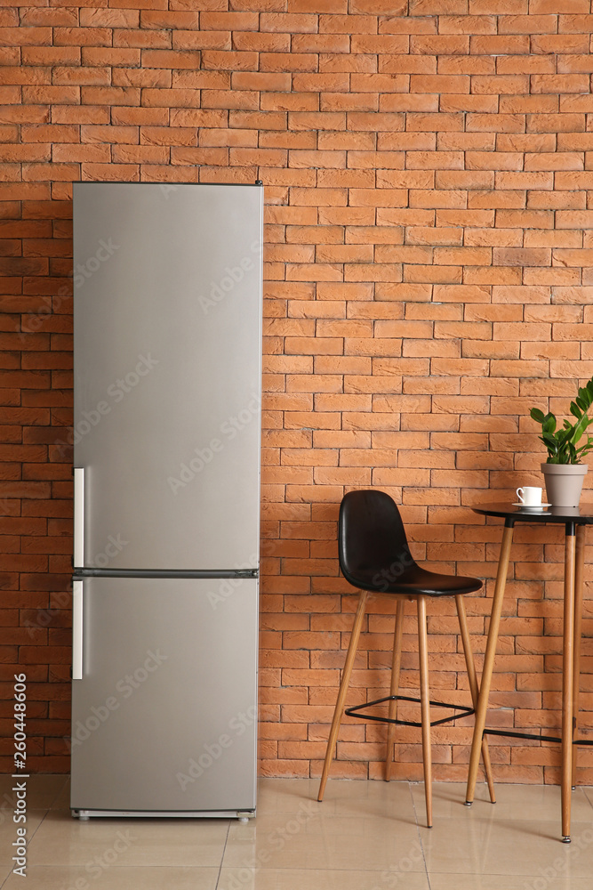 Modern fridge, table and chair in kitchen