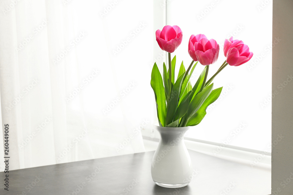 Vase with beautiful tulip flowers on table near window