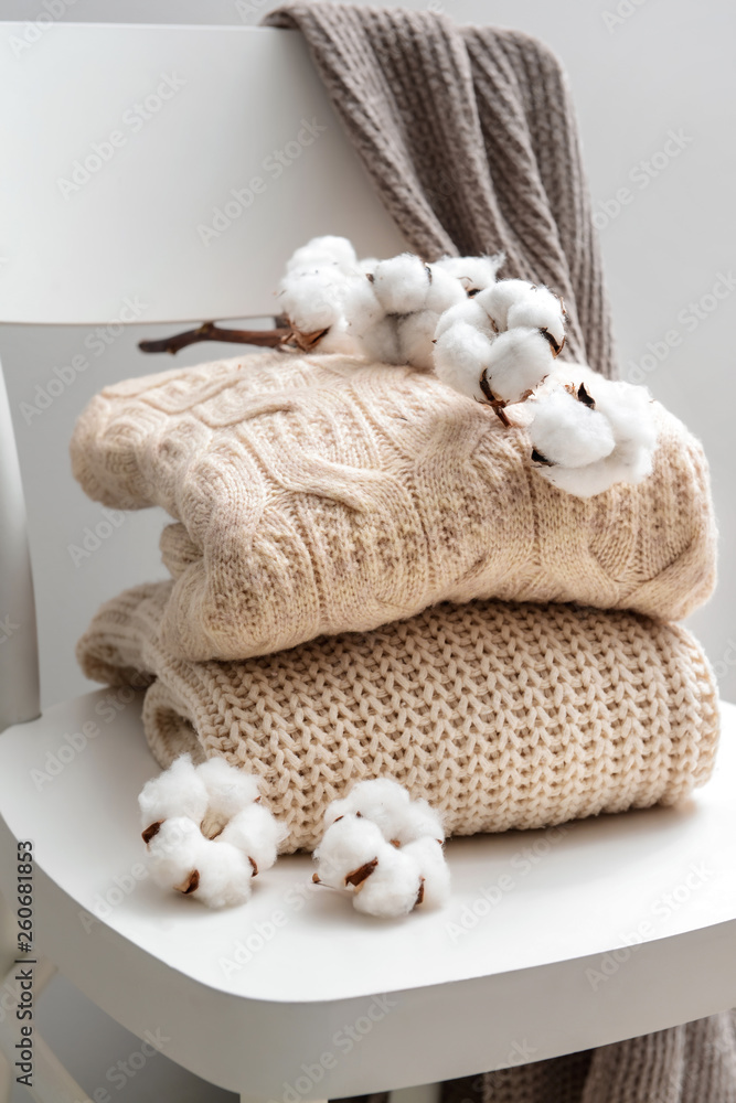 Knitted sweaters with cotton flowers on white chair