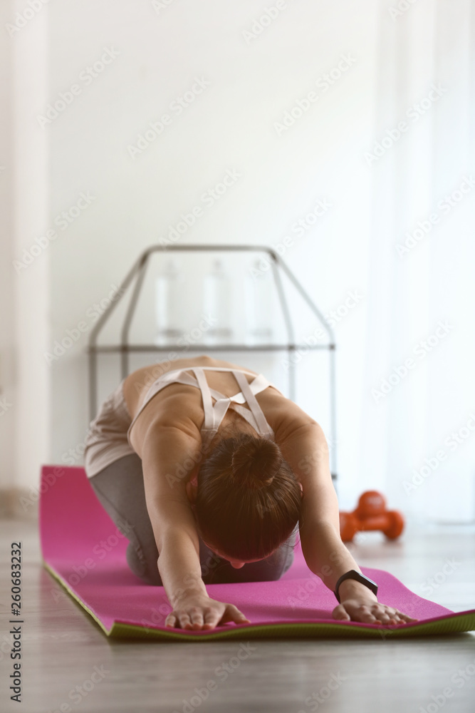Sporty young woman practicing yoga indoors