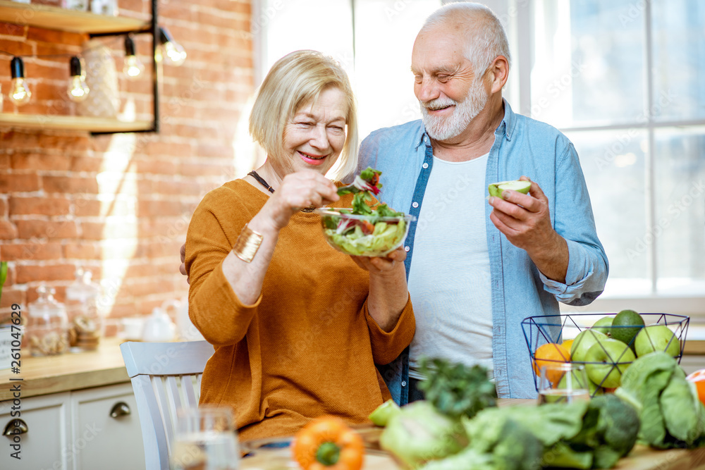 一对快乐的老年夫妇的画像，家里的厨房里有沙拉和健康食品。概念