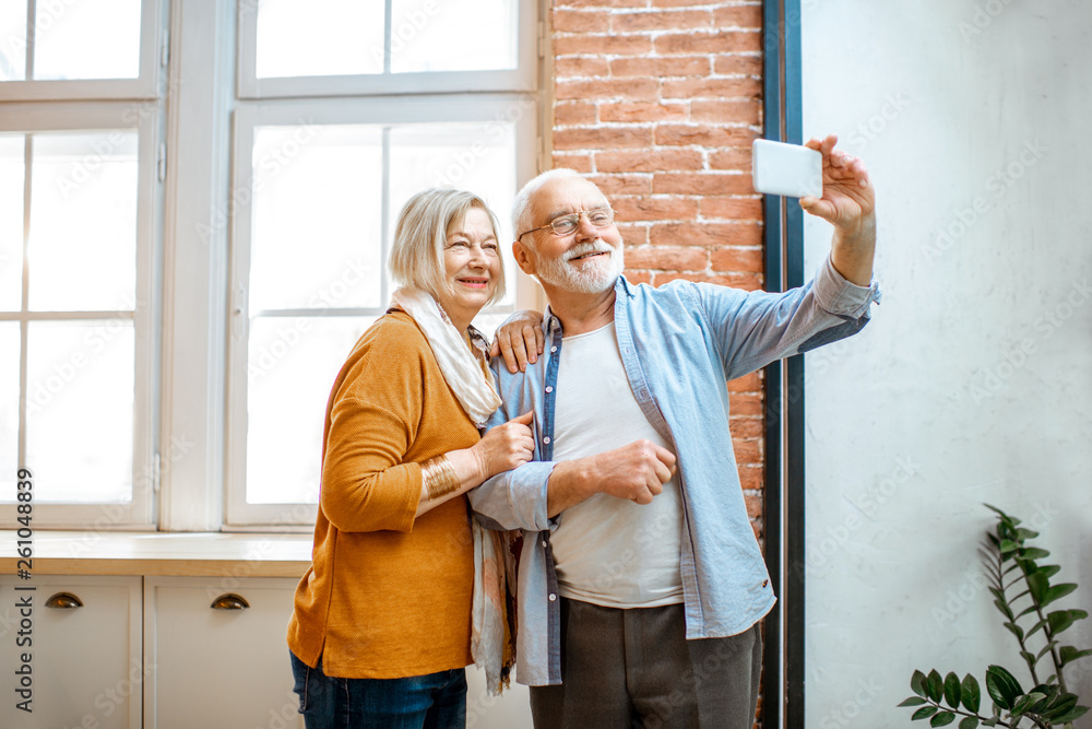 幸福的老年夫妇在家里用智能手机自拍或在线聊天
