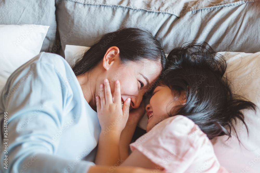 亚洲妈妈在卧室亲吻女儿，带着爱和温暖的家庭观念