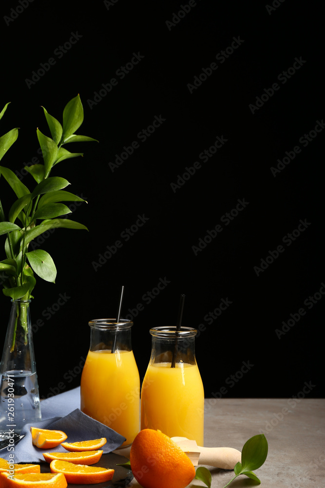 深色背景下桌上摆着几瓶美味的橙汁
