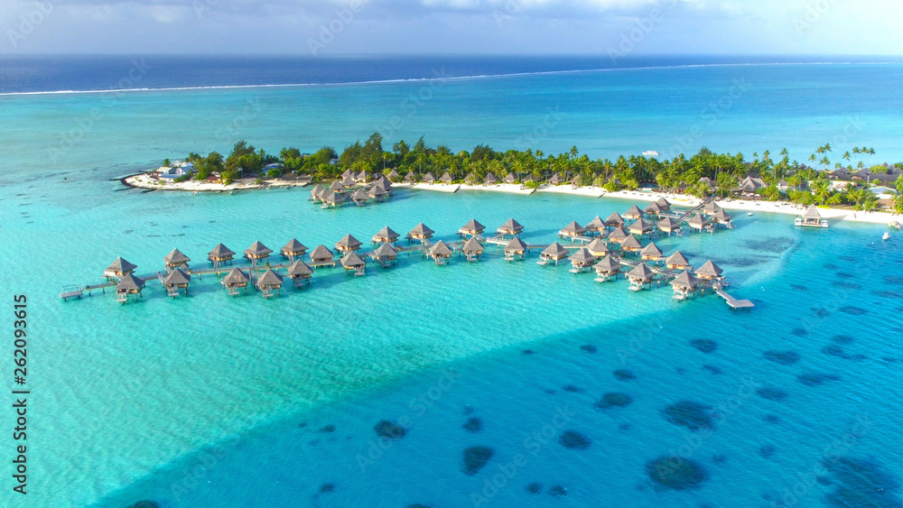 DRONE: Stunning view of the wooden overwater villas above the turquoise sea.