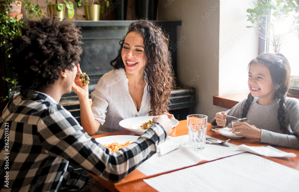 快乐的非裔美国人一家在餐厅一起吃午饭，玩得很开心