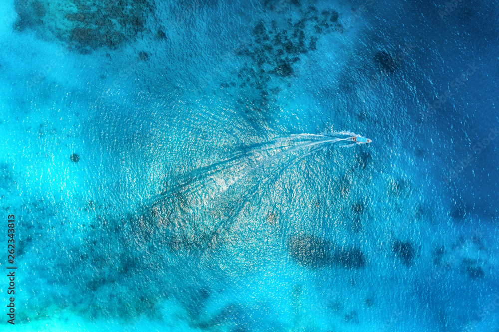 夏日日落时，渔船在清澈的蓝色水中的鸟瞰图。船的无人机俯视图