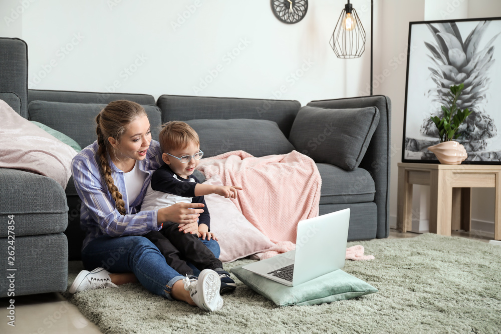 Young mother with little son watching cartoons at home