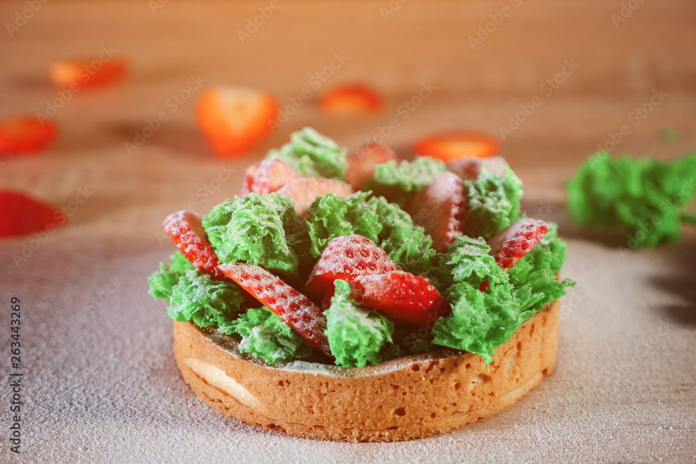 迷你蛋糕配草莓片、绿色蔬菜和奶油饼干和糖粉。