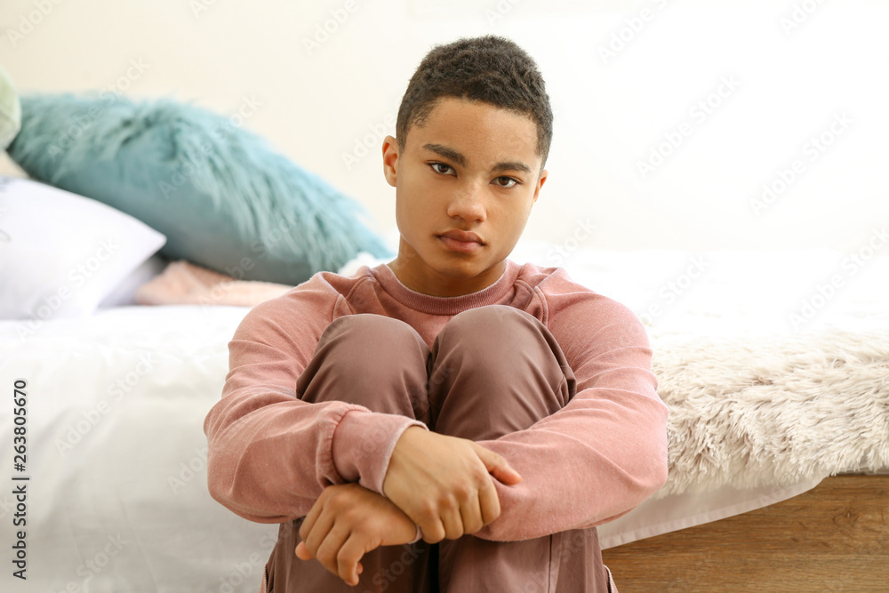 悲伤的非裔美国少年坐在卧室里